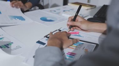 Hesap makinesi kullanan ve masa üzerinde grafik ve belgelerle muhasebe yapan işadamlarının ellerini kapat.