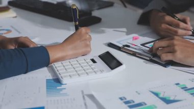 Hesap makinesi kullanan ve masa üzerinde grafik ve belgelerle muhasebe yapan işadamlarının ellerini kapat.