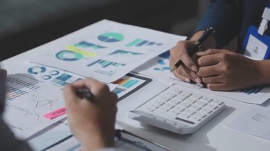 Hesap makinesi kullanan ve masa üzerinde grafik ve belgelerle muhasebe yapan işadamlarının ellerini kapat.