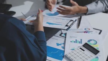 Hesap makinesi kullanan ve masa üzerinde grafik ve belgelerle muhasebe yapan işadamlarının ellerini kapat.