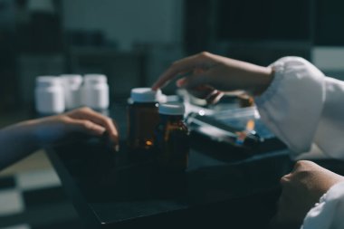 Elinde ilaç şişesi olan kadın doktor hastanın yan etkileri için ilaç kalitesini kontrol ediyor ve hasta bilgilerini hastanede kaydediyor. tıbbi ve sağlık hizmetleri kavramı
