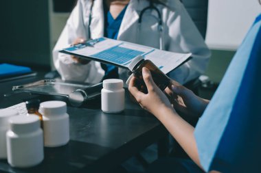 Elinde ilaç şişesi olan kadın doktor hastanın yan etkileri için ilaç kalitesini kontrol ediyor ve hasta bilgilerini hastanede kaydediyor. tıbbi ve sağlık hizmetleri kavramı