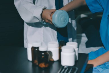 Fizyoterapist, halter egzersizinde bir kadına yardım ediyor.