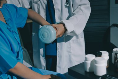 Fizyoterapist, halter egzersizinde bir kadına yardım ediyor.