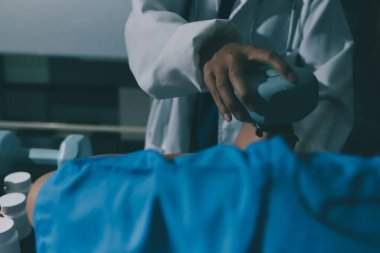 Fizyoterapist, halter egzersizinde bir kadına yardım ediyor.