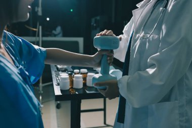 Fizyoterapist, halter egzersizinde bir kadına yardım ediyor.