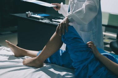 Hastane odasında yaralı bir kadının ayak bileğini inceleyen ve destekleyen doktor, burkulma ya da kırık için tıbbi yardım ve tedavi sunuyor.