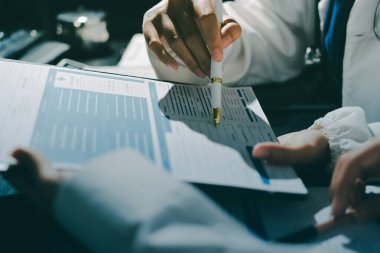 Two doctors and a female nurse meet at a table in the hospital, collaborating on medical tasks using laptops and computers