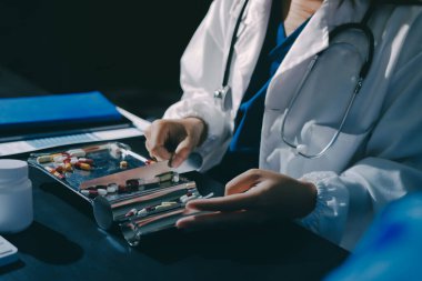 Elinde ilaç şişesi olan kadın doktor hastanın yan etkileri için ilaç kalitesini kontrol ediyor ve hasta bilgilerini hastanede kaydediyor. tıbbi ve sağlık hizmetleri kavramı
