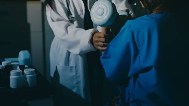 Fizyoterapist, halter egzersizinde bir kadına yardım ediyor.