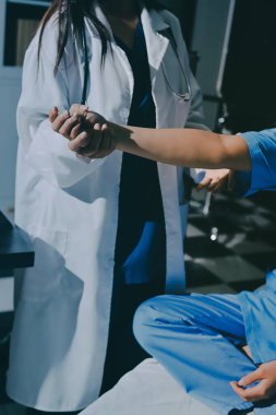 Hastane odasında hastanın dirseğini muayene eden doktor.