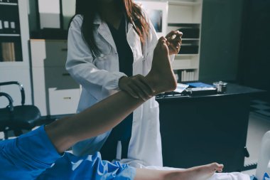 Hastane odasında yaralı bir kadının ayak bileğini inceleyen ve destekleyen doktor, burkulma ya da kırık için tıbbi yardım ve tedavi sunuyor.