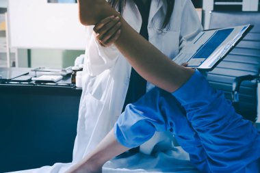 Hastane odasında yaralı bir kadının ayak bileğini inceleyen ve destekleyen doktor, burkulma ya da kırık için tıbbi yardım ve tedavi sunuyor.