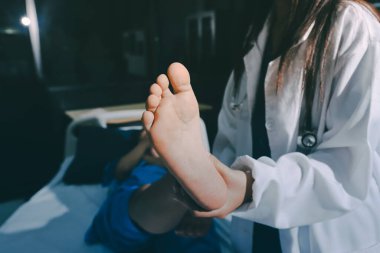 Hastane odasında yaralı bir kadının ayak bileğini inceleyen ve destekleyen doktor, burkulma ya da kırık için tıbbi yardım ve tedavi sunuyor.