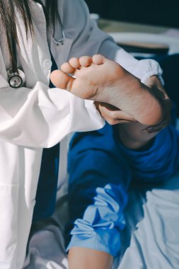 Hastane odasında yaralı bir kadının ayak bileğini inceleyen ve destekleyen doktor, burkulma ya da kırık için tıbbi yardım ve tedavi sunuyor.