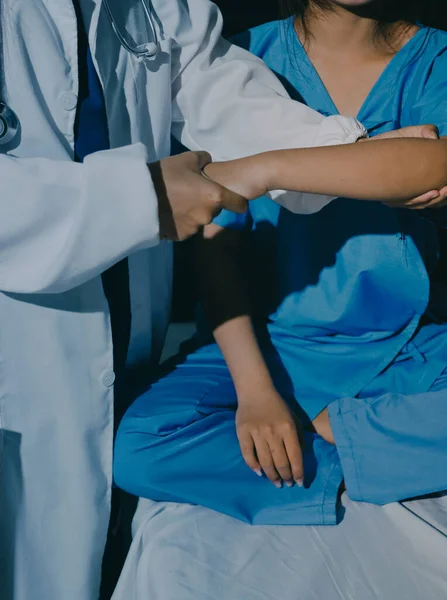 Hastane odasında hastanın dirseğini muayene eden doktor.