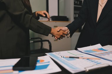 Genç iş adamları ofiste el sıkışıyor. Başarılı toplantı sona eriyor. Üç kişi. Geniş ekran panoramik