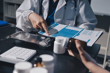 Elinde ilaç şişesi olan kadın doktor hastanın yan etkileri için ilaç kalitesini kontrol ediyor ve hasta bilgilerini hastanede kaydediyor. tıbbi ve sağlık hizmetleri kavramı