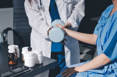 Fizyoterapist, halter egzersizinde bir kadına yardım ediyor.