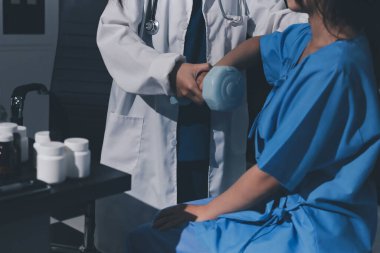 Fizyoterapist, halter egzersizinde bir kadına yardım ediyor.