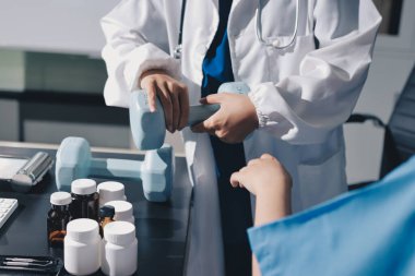 Fizyoterapist, halter egzersizinde bir kadına yardım ediyor.