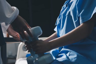 Fizyoterapist, halter egzersizinde bir kadına yardım ediyor.