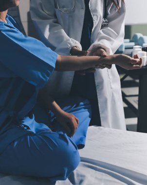 Hastane odasında hastanın dirseğini muayene eden doktor.