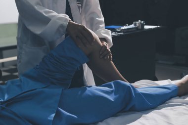 Hastane odasında yaralı bir kadının ayak bileğini inceleyen ve destekleyen doktor, burkulma ya da kırık için tıbbi yardım ve tedavi sunuyor.