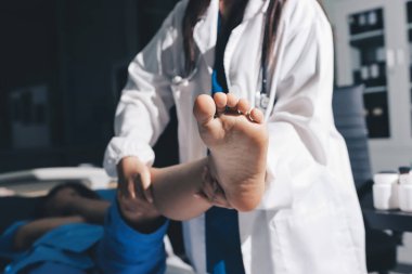 Hastane odasında yaralı bir kadının ayak bileğini inceleyen ve destekleyen doktor, burkulma ya da kırık için tıbbi yardım ve tedavi sunuyor.