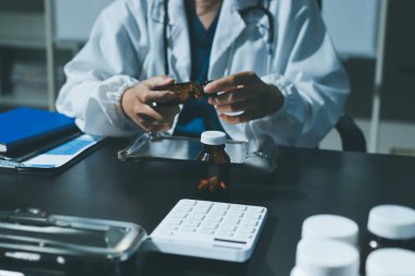 Elinde ilaç şişesi olan kadın doktor hastanın yan etkileri için ilaç kalitesini kontrol ediyor ve hasta bilgilerini hastanede kaydediyor. tıbbi ve sağlık hizmetleri kavramı