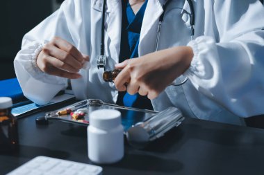 Elinde ilaç şişesi olan kadın doktor hastanın yan etkileri için ilaç kalitesini kontrol ediyor ve hasta bilgilerini hastanede kaydediyor. tıbbi ve sağlık hizmetleri kavramı