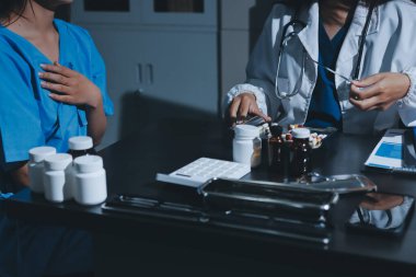 Elinde ilaç şişesi olan kadın doktor hastanın yan etkileri için ilaç kalitesini kontrol ediyor ve hasta bilgilerini hastanede kaydediyor. tıbbi ve sağlık hizmetleri kavramı