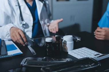 Elinde ilaç şişesi olan kadın doktor hastanın yan etkileri için ilaç kalitesini kontrol ediyor ve hasta bilgilerini hastanede kaydediyor. tıbbi ve sağlık hizmetleri kavramı