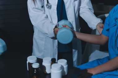 Fizyoterapist, halter egzersizinde bir kadına yardım ediyor.