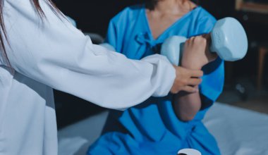 Fizyoterapist, halter egzersizinde bir kadına yardım ediyor.