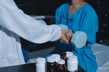 Fizyoterapist, halter egzersizinde bir kadına yardım ediyor.