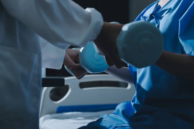 Fizyoterapist, halter egzersizinde bir kadına yardım ediyor.