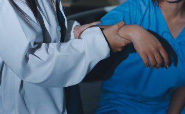 Hastane odasında hastanın dirseğini muayene eden doktor.