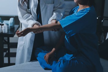 Hastane odasında hastanın dirseğini muayene eden doktor.