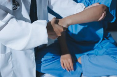 Hastane odasında hastanın dirseğini muayene eden doktor.