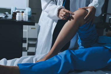 Hastane odasında yaralı bir kadının ayak bileğini inceleyen ve destekleyen doktor, burkulma ya da kırık için tıbbi yardım ve tedavi sunuyor.