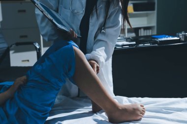 Hastane odasında yaralı bir kadının ayak bileğini inceleyen ve destekleyen doktor, burkulma ya da kırık için tıbbi yardım ve tedavi sunuyor.