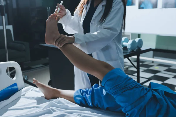 Hastane odasında yaralı bir kadının ayak bileğini inceleyen ve destekleyen doktor, burkulma ya da kırık için tıbbi yardım ve tedavi sunuyor.