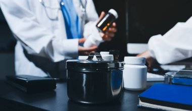 Two doctors and a female nurse meet at a table in the hospital, collaborating on medical tasks using laptops and computers