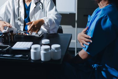 Elinde ilaç şişesi olan kadın doktor hastanın yan etkileri için ilaç kalitesini kontrol ediyor ve hasta bilgilerini hastanede kaydediyor. tıbbi ve sağlık hizmetleri kavramı