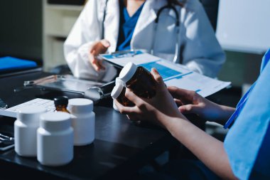 Elinde ilaç şişesi olan kadın doktor hastanın yan etkileri için ilaç kalitesini kontrol ediyor ve hasta bilgilerini hastanede kaydediyor. tıbbi ve sağlık hizmetleri kavramı