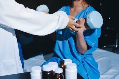 Fizyoterapist, halter egzersizinde bir kadına yardım ediyor.