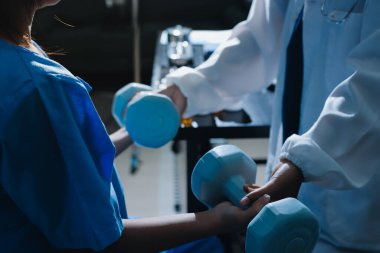 Fizyoterapist, halter egzersizinde bir kadına yardım ediyor.