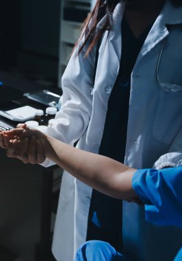 Hastane odasında hastanın dirseğini muayene eden doktor.