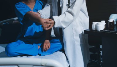 Hastane odasında hastanın dirseğini muayene eden doktor.